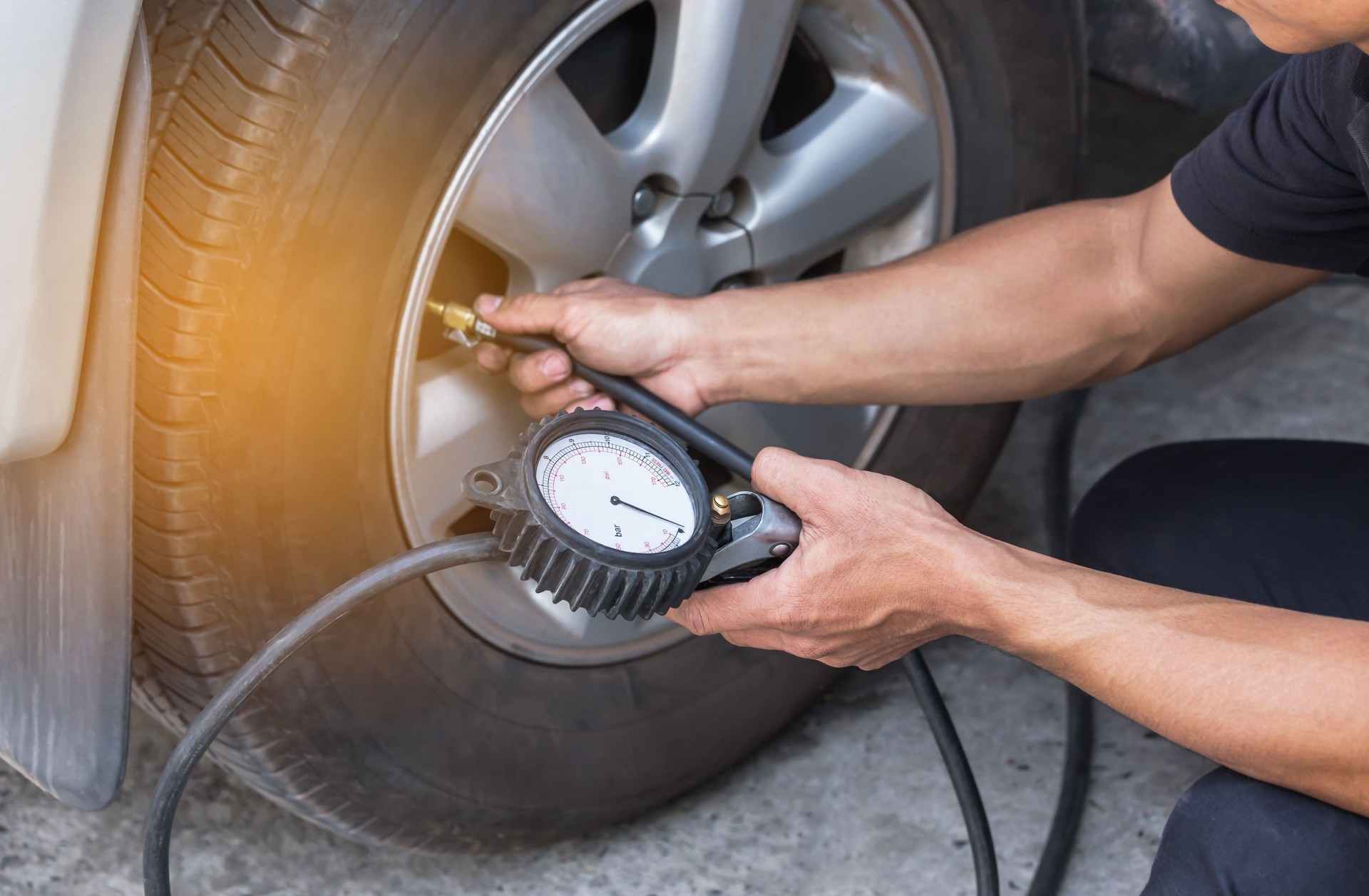 Close up mechanic inflating tire and checking air pressure with gauge pressure