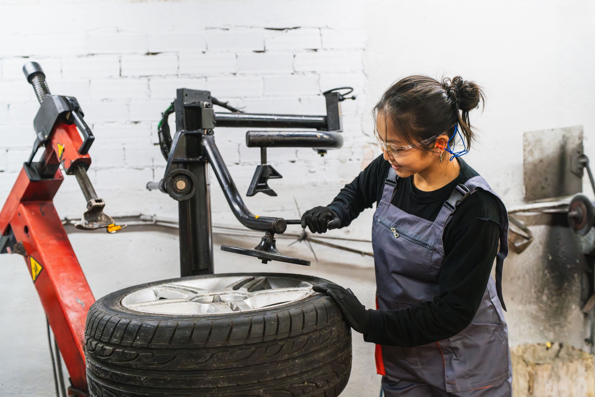 Female mechanic repairing car tire using machine in workshop